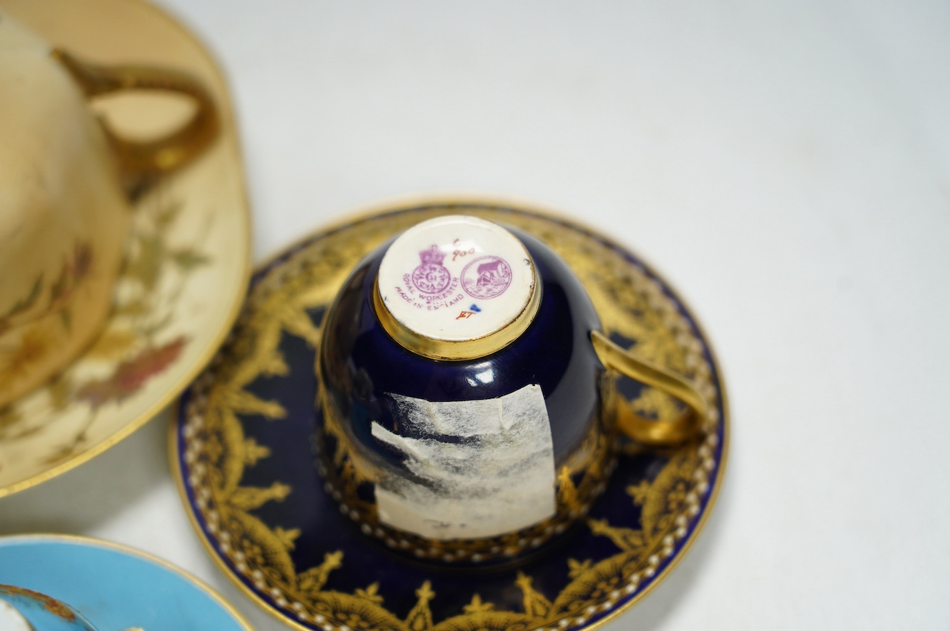 Four miniature Worcester cups and saucers, including a blush ivory ground, one signed G Johnson, largest 12.5cm wide. Condition - fair